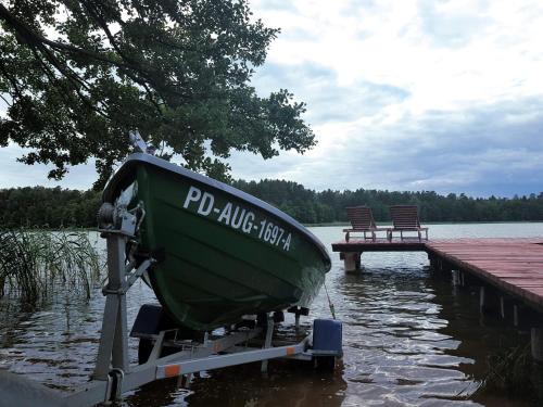 a green boat sitting on a dock next to a bench at Dwa Pomosty in Augustów