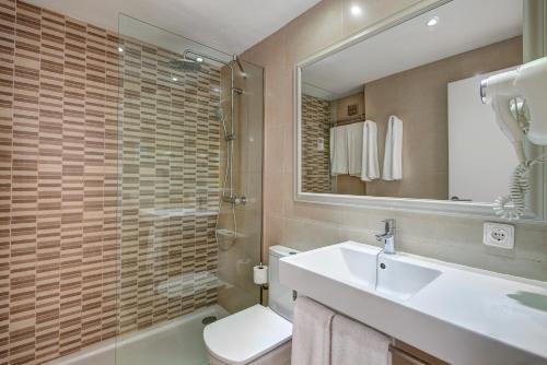 a bathroom with a sink and a toilet and a mirror at Apartamentos Cala d'Or Playa in Cala d´Or