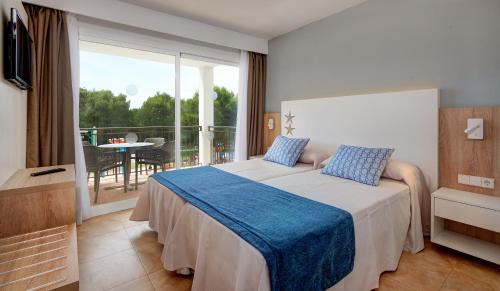 Habitación de hotel con cama y balcón en Apartamentos Cala d'Or Playa, en Cala d´Or