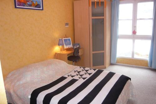 a bedroom with a bed and a desk and a window at Les Comptoirs in Saint Malo