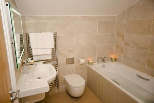 a bathroom with a tub and a toilet and a sink at The Lodge in Hunstanton