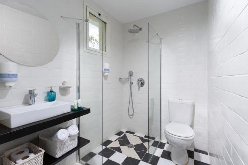 La salle de bains est pourvue de toilettes, d'un lavabo et d'une douche. dans l'établissement Metulla Travel Hotel, à Metulla