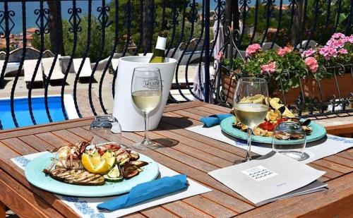 a table with two plates of food and wine glasses at Hotel Garden Riviera in Santa Maria di Castellabate