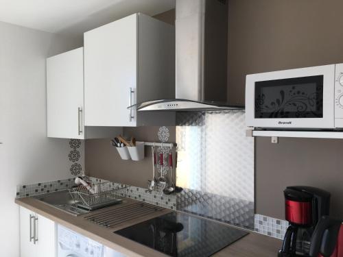 une cuisine avec des armoires blanches et un micro-ondes dans l'établissement Goeland 3, studio classé climatisé, wifi, terrasses petite vue mer latérale au 3 ème étage sans ascenseur, à Toulon