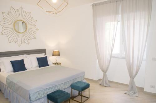 um quarto branco com uma cama e 2 bancos azuis em Palazzo Spasiano rooms - SORRENTO CENTER em Sorrento