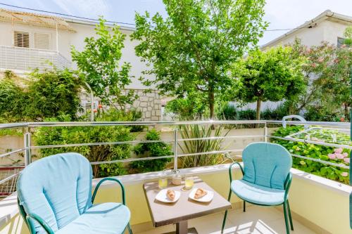 a balcony with two blue chairs and a table and a table and chairs at Holiday house Barbara in Supetar