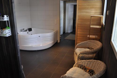 uma casa de banho com banheira e 2 cadeiras de vime em Tuhannen Tarinan Talo em Kannuskoski