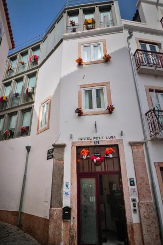 a white building with flowers on the windows and a door at House Petit Lusa in Lisbon