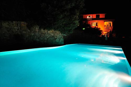 a swimming pool at night with a house in the background at Hotel Su Lithu in Bitti