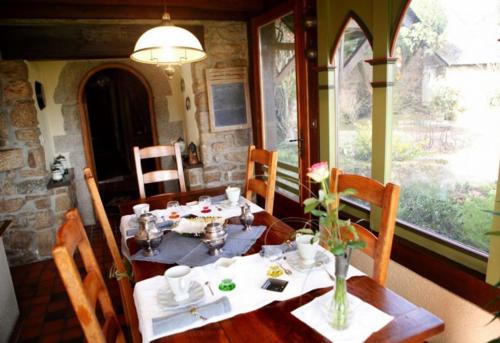 une salle à manger avec une table en bois et des fleurs. dans l'établissement La Tourelle 22, à Quintin