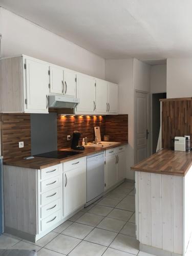 une cuisine avec des armoires blanches et des comptoirs en bois dans l'établissement Villa dans les dunes, à Torreilles