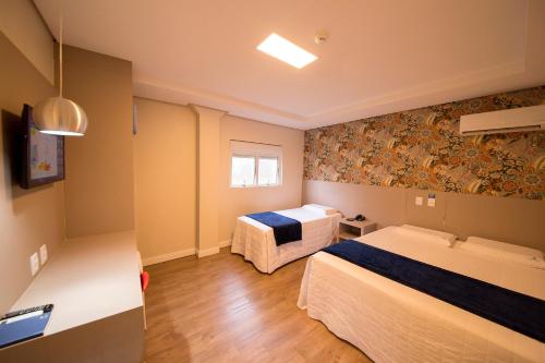 um quarto de hotel com duas camas e uma janela em Hiber Hotel - Acesso a Chapecó em Chapecó