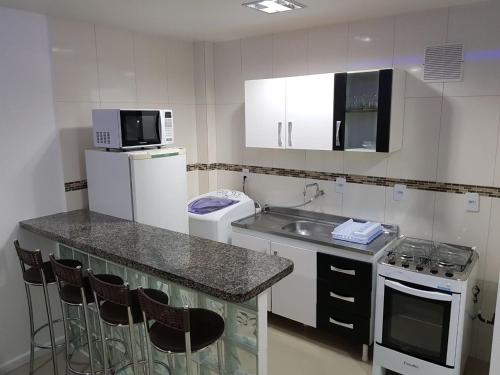 een kleine keuken met een wastafel en een magnetron bij Condominio Galeao in Florianópolis