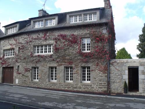 - un vieux bâtiment en pierre avec des fleurs rouges dans l'établissement La Tourelle 22, à Quintin