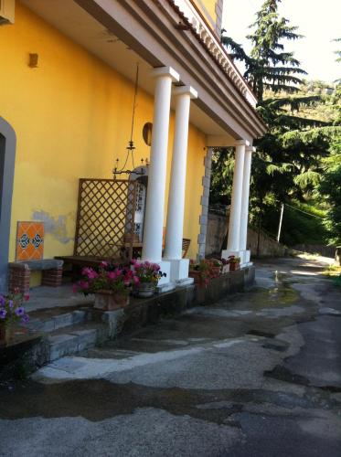 a yellow house with white columns and flowers on the steps at A Casa Di Agata in Pellezzano