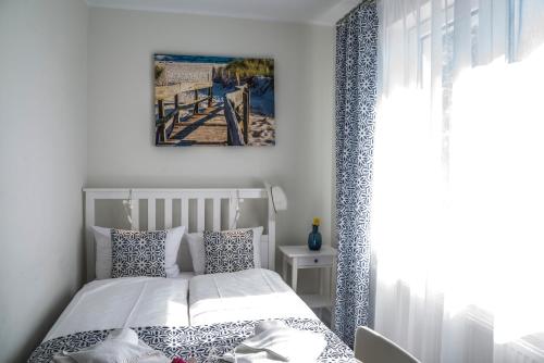 Apartamenty Mewa في مينززدرويه: غرفة نوم مع سرير ووسائد زرقاء وبيضاء