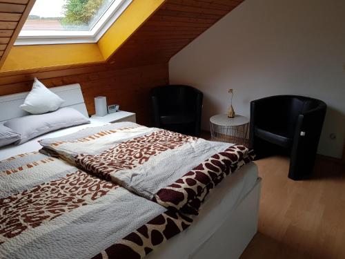 a bedroom with a bed with two chairs and a window at Ferienwohnung Hedi in Mertloch