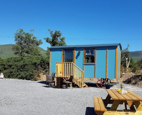 a blue and yellow tiny house with a picnic table at Dingle Way Glamping in Anascaul