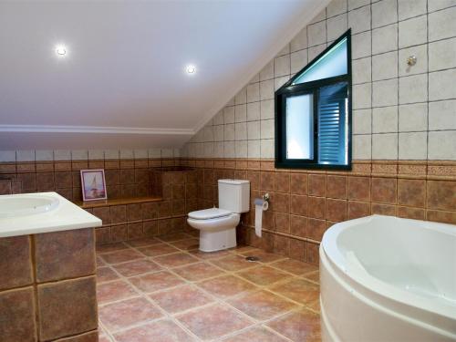 a bathroom with a toilet and a sink and a window at Vivienda de uso turístico Eido de Roque in Mondariz