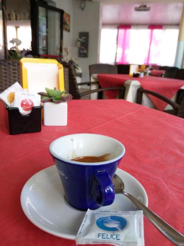 a cup of coffee sitting on a plate on a table at Hotel AnnaMare in Rimini