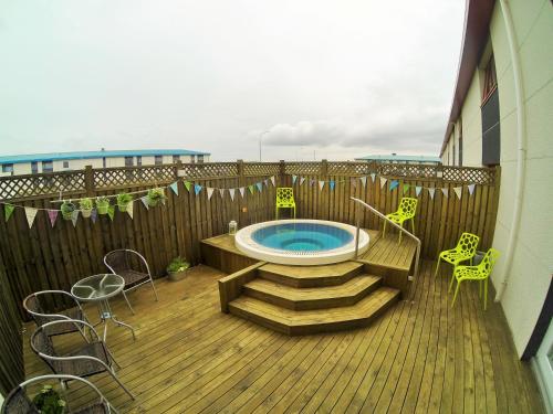 a hot tub on a deck with chairs and a table at Eldey Airport Hotel in Keflavík