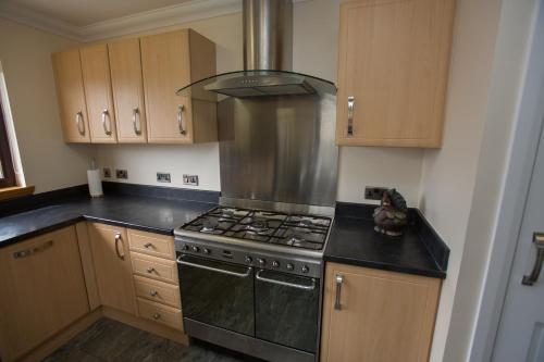 a kitchen with a stove top oven and wooden cabinets at GOLFVIEW 4 in Buckie