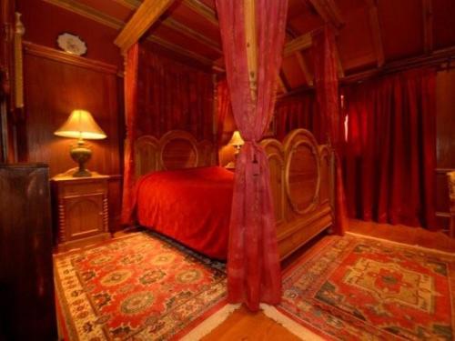 a bedroom with a red bed and red curtains at Wolds Village Hotel in Bainton