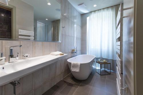 a bathroom with a large white tub and a sink at Riva Palace in Split