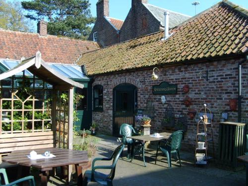 a patio with tables and chairs in front of a brick building at Wolds Village Hotel in Bainton