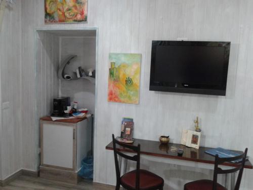 a living room with a table and a television on a wall at La Casetta Di Anna in Castel Lagopesole