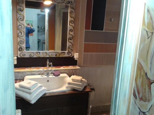 y baño con lavabo, espejo y toallas. en La Casetta Di Anna en Castel Lagopesole