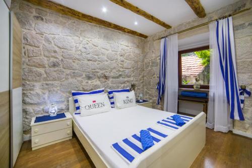 um quarto com uma cama branca e uma parede de pedra em Apartments Stinice em Gradac