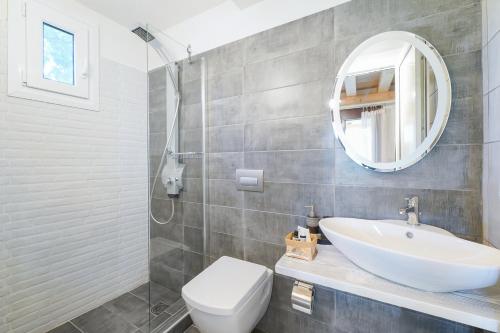 a bathroom with a sink and a toilet and a mirror at Natura Bungalows-Villa in Limenas