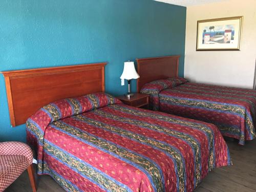two beds in a hotel room with blue walls at Chaparral Motel in Port Lavaca