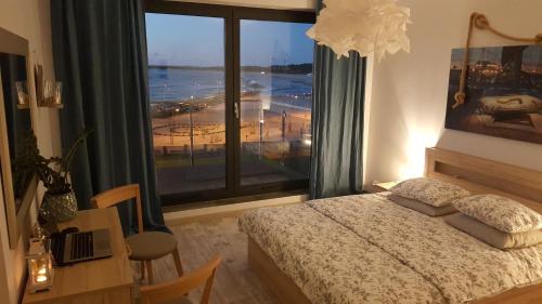 sypialnia z łóżkiem i dużym oknem w obiekcie Apartament Morski przy Latarni w Darłówku