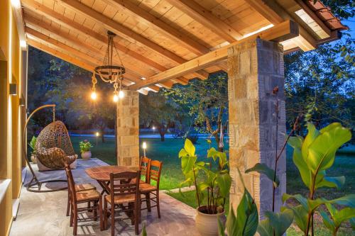 a patio with a table and chairs under a wooden pergola at Natura Bungalows-Villa in Limenas