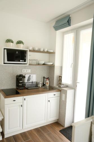 a kitchen with white cabinets and a microwave at Morzsi Apartman in Szilvásvárad