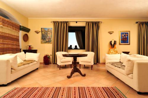 a living room with white furniture and a table at Hotel Su Lithu in Bitti