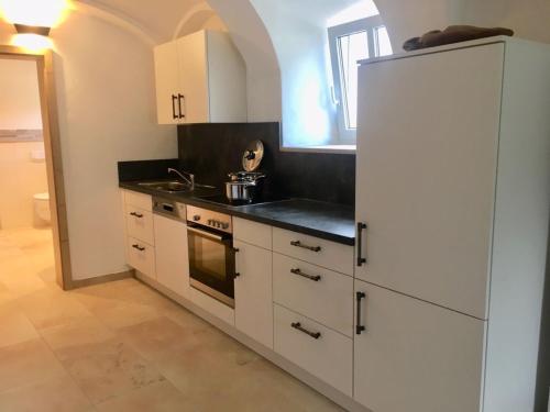 a kitchen with white cabinets and a white refrigerator at Ferienwohnung zum Dorfwirt in Riedenburg