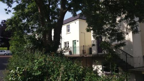 a white house with a balcony and trees at 4 Bleach Green Apartments in Ballycastle