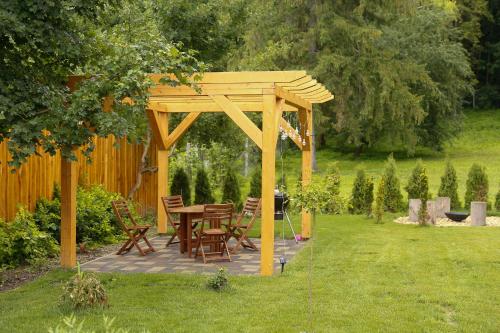 a wooden gazebo with a table and chairs in a yard at Morzsi Apartman in Szilvásvárad