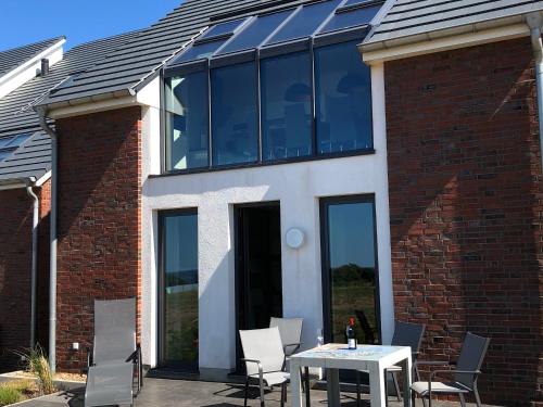 a house with glass windows and a table and chairs at Tor zum Meer in Helgoland
