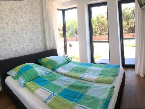 a bed with green and blue pillows in a room with windows at Tor zum Meer in Helgoland