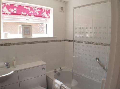 een badkamer met een douche en een bad en een raam bij Sunny View, 87 Brambles Chine in Freshwater