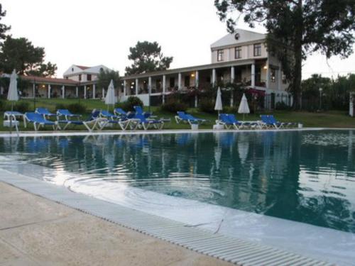 ein Pool mit blauen Stühlen und ein Gebäude in der Unterkunft Odeceixe Bungalow-Parque de Campismo Sao Miguel in Odeceixe