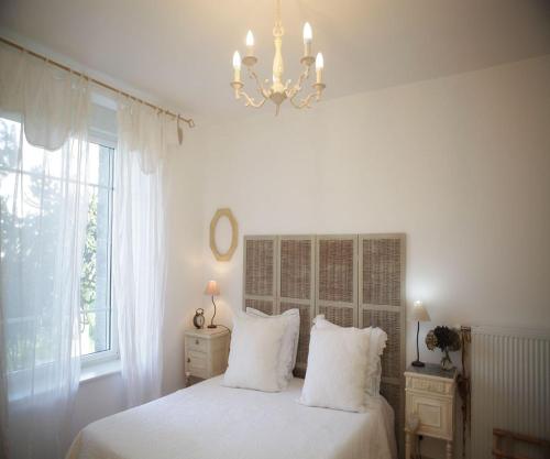 a bedroom with a bed with white sheets and a chandelier at Château Bily B&B Hôtel in La Chèze