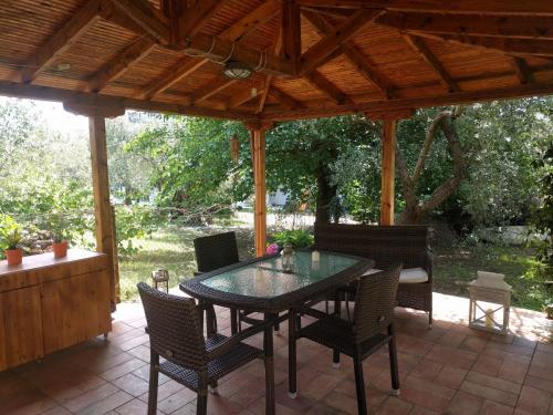 un patio con mesa y sillas bajo un techo de madera en House Christie, en Chrysi Ammoudia