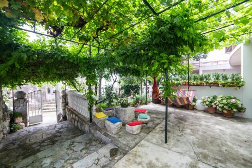 a garden with a pergola with trees and plants at Apartments Stinice in Gradac