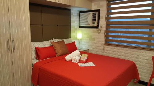 a bedroom with a red bed and a window at Khalil's Horizons 101 Studio Type Condominium in Cebu City