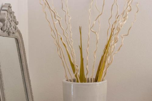 een witte vaas met een plant erin naast een spiegel bij Hotel Aurora in Lignano Sabbiadoro